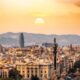 Sunset over Barcelona skyline featuring the Columbus Monument, Torre Glòries, and historic city architecture.